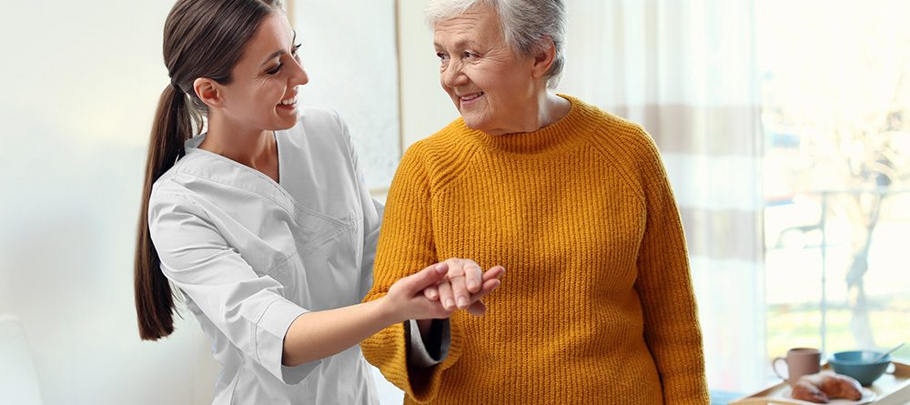 Pflegekraft stützt eine ältere Frau beim Gehen
